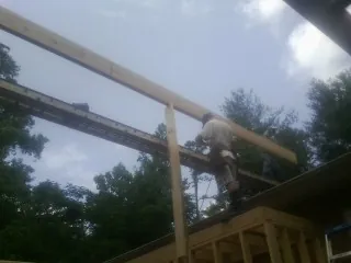 Carpenter setting a ridge beam over a new addition frame — Ice Dam Removal by Roofing Brothers in Fort Ann