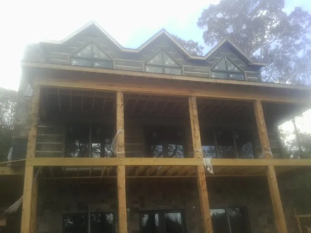 Dormers and porch framing on a large log home under construction — Roof Coating work by our crew in Fort Ann