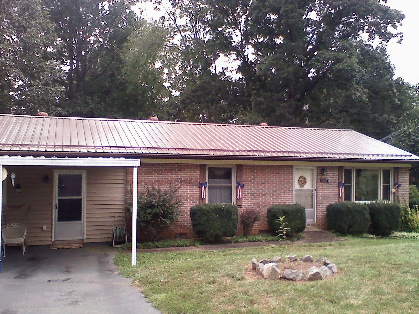 Bronze metal roof and carport on a brick ranch home — Roof Repair work by our crew in Fort Ann