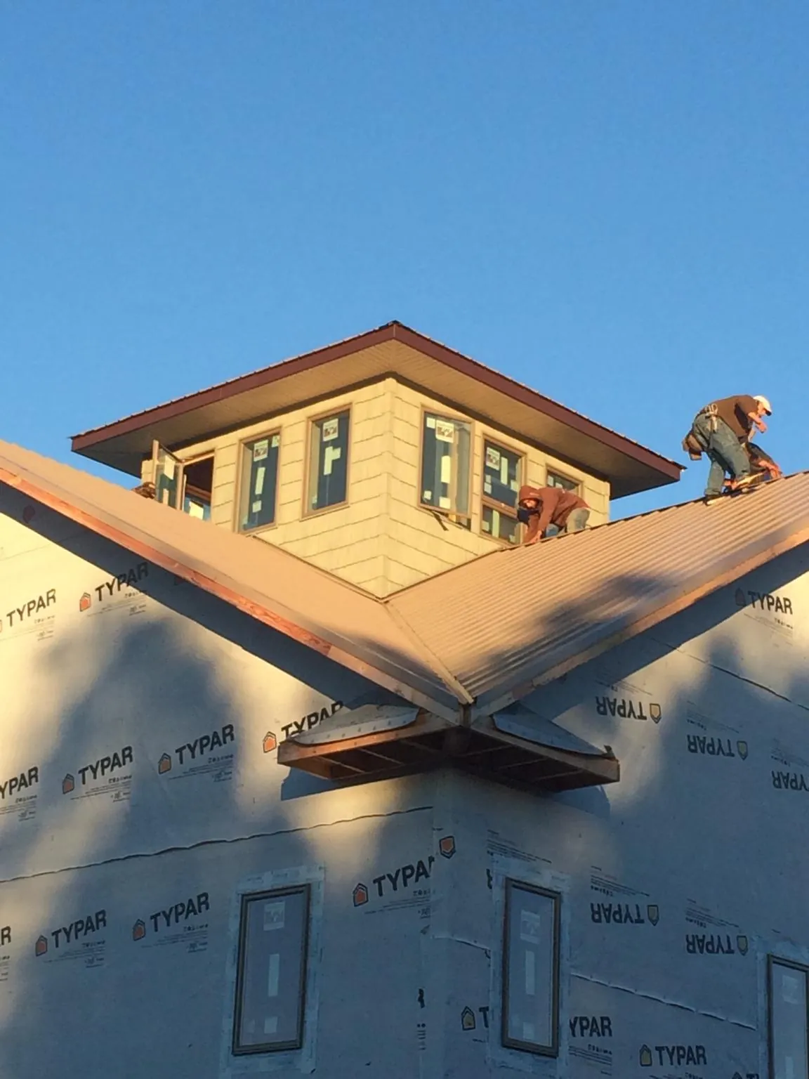 Roofers working around a rooftop cupola on a new metal roof at sunset — Roof Waterproofing in Fort Ann by Roofing Brothers